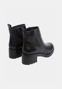 Botas de tobillo de cuero negro con un diseño elegante, cremalleras laterales y suelas de goma gruesas. Textura suave y forma de puntera redondeada.