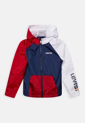 Dziecięca kurtka przeciwdeszczowa Levi’s w stylu color-block z czerwonymi, granatowymi i białymi panelami, z przodu zamek błyskawiczny, kaptur oraz logo Levi’s na piersi i rękawie.