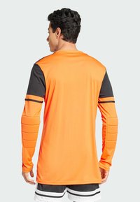 Langärmliges Torwarttrikot in leuchtendem Orange mit schwarzen Akzenten. Verfügt über gepolsterte Abschnitte an den Ellbogen und einem glatten, leichten Stoff.