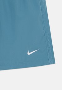 Šviesiai mėlyni sportiniai šortai, pagaminti iš minkštos medžiagos, su baltu Nike logotipu prie apvados ir kontrastinga šonine siūle.