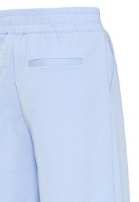Pantalon bleu clair avec une ceinture élastique et une poche arrière à fente horizontale sur le côté droit.
