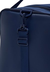 Σκούρο μπλε ορθογώνια γωνία τσάντας με ρυθμιζόμενο ιμάντα με πλαστικό κλιπ και φερμουάρ στο πάνω μέρος.