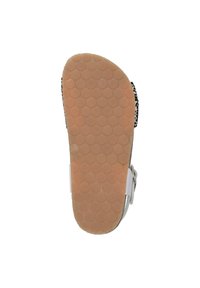 Platte sandaalzool met een getextureerd tan rubberoppervlak met cirkelvormige patronen, witte bandjes en een zwart-wit bloemenprintdesign.