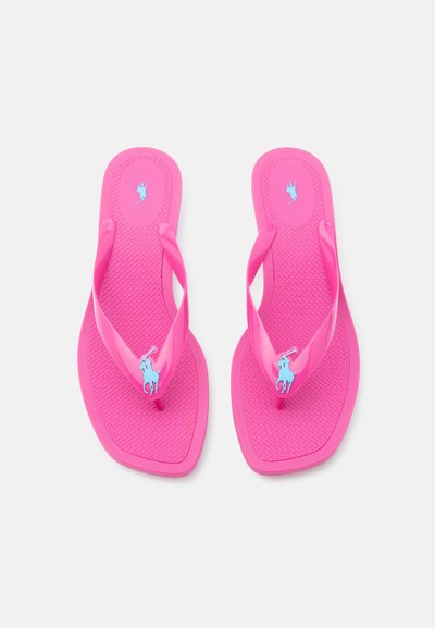 Φωτεινά ροζ σαγιονάρες με υφή στη σόλα, διακοσμημένες με μπλε λογότυπα ιππέων πόλο σε ιμάντες και περιοχές της φτέρνας, εμφανιζόμενες σε λευκό φόντο.