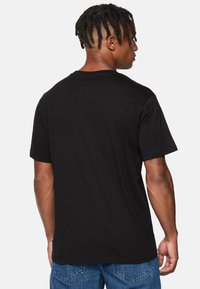 Sort bomulds t-shirt med korte ærmer, rund halsudskæring og lige kant. Har en glat tekstur og ingen synlige logoer eller mønstre.