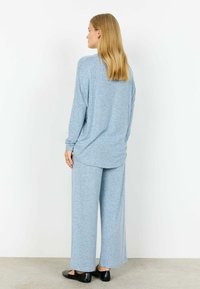 Set de haine confortabile albastru deschis, format dintr-un top cu mâneci lungi și croială lejeră și pantaloni cu picioare largi, confecționați dintr-un material moale și texturat.