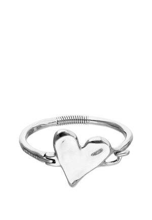 Bracciale d'argento con un elemento centrale a forma di cuore irregolare e liscia, e un dettaglio a spirale sul cinturino.