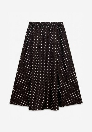 Longue jupe noire évasée, avec une taille élastique et des pois blancs régulièrement espacés, présentée sur un fond blanc uni.