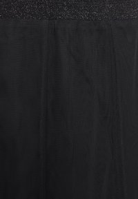 Jupe en tulle noir avec une ceinture texturée et scintillante. Le tissu est léger, semi-transparent et a une apparence superposée.