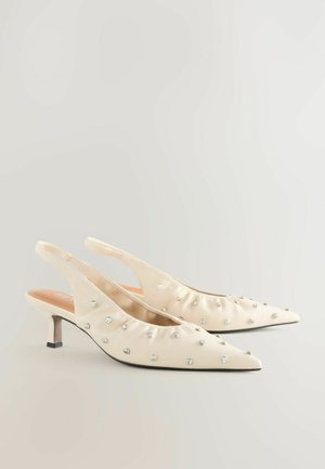 Beige Slingback-Pumps mit spitzen Zehen, verziert mit silbernen Strasssteinen, ausgestattet mit kitten heels und weichem Satinmaterial.