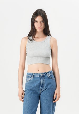 Top court gris avec texture côtelée, encolure ronde et sans manches, associé à un jean bleu taille haute.