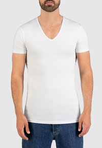 Witte T-shirt met korte mouwen en V-hals, gemaakt van rekbaar materiaal, met een aansluitend ontwerp dat het lichaam accentueert, gecombineerd met blauwe denim shorts.