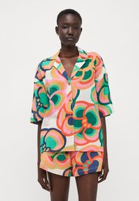 Kortermet, multicolor skjorte og shorts-sett i lett stoff, med et dristig blomstermønster i grønt, rosa og marineblå aksenter.