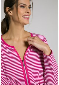 Stribet zip-up top med rosa og hvide vandrette striber, en sølvlynlås og en rund halsudskæring. Blødt stof med en behagelig pasform.