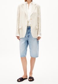 Valkoinen pellavableiseri, valkoinen napillinen paita, vaaleansiniset farkkushortsit ja mustat liukusandaalit. Suora leikkaus ja rento tyyli.