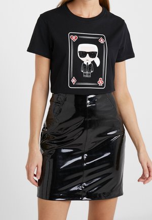 Czarna bawełniana koszulka z grafiką postaci w okularach przeciwsłonecznych. Do tego błyszcząca, czarna mini spódniczka.