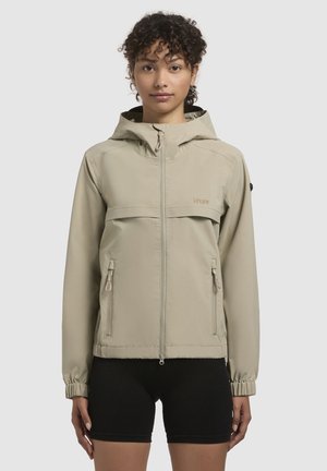 Chaqueta ligera beige con capucha, frontal con cremallera y dos bolsillos laterales. Presenta puños elásticos y un bolsillo en el pecho. Textura suave.