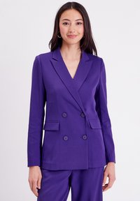 Blazer double boutonnage violet avec col à cran, deux poches avant et boutons ronds, fabriqué à partir d'un tissu lisse et texturé.