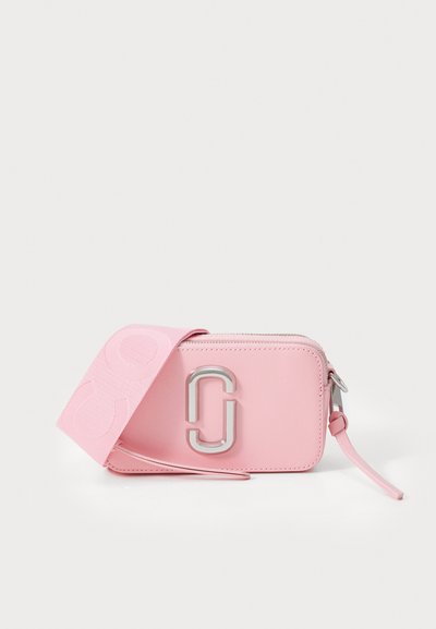 Petit sac en cuir rose rectangulaire avec un logo double-J en argent et une large bandoulière en tissu reposant devant.