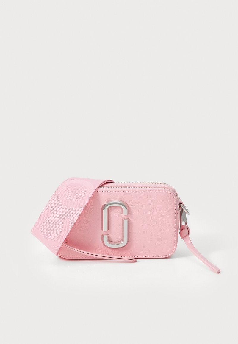 Piccola borsa a tracolla rettangolare rosa in pelle con logo doppio J in argento e ampia tracolla in tessuto, poggiata davanti.