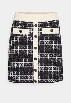 Schwarzer und weißer Tweed-Rock mit einem gestrickten Bund, vorderem Knopfverschluss und zwei Brusttaschen mit kontrastierenden Akzenten und strukturiertem Muster.