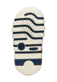 Suela de zapato con una base crema, acentos azules y textura ondulada. Presenta agujeros de aire y detalles de marca en relieve para una mayor transpirabilidad.