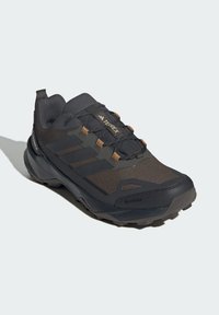 Sorte vandrestøvler med en struktureret overdel og brune accenter. Funktioner inkluderer et Gore-Tex mærke, snøresystem og en robust sål for godt greb.