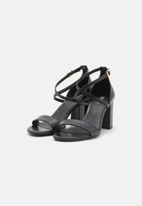 Sandali neri con tacco a blocco, caratterizzati da fasce incrociate e design open toe. Realizzati in pelle liscia con dettagli minimi.