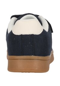 Marinblå sneaker med en mocka-liknande yta, vit vadderad krage och sula av gummirubber. Har en låg design och kardborreband.