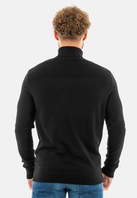 Suéter negro de punto con un alto cuello, textura acanalada en los hombros, mangas ajustadas y un diseño texturizado en la espalda.