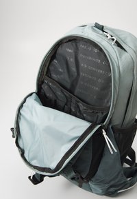 Ryggsäck i ljusblått och svart tyg, med ett stort huvudfack, innerväskor och en framficka med dragkedja för tillbehör.