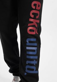 Black sweatpants with red "eckō" and blue "united." logos along the sides. Made of soft fabric with a regular-fit design and elastic cuffs.