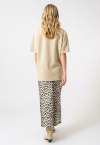 Top beige de manga corta combinado con una falda larga de estampado de leopardo. El conjunto cuenta con un corte relajado y una textura suave.