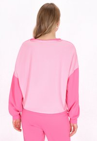 Felpa rosa oversized con maniche lunghe, caratterizzata da un design bicolore e un collo grezzo. Tessuto morbido con vestibilità comoda.