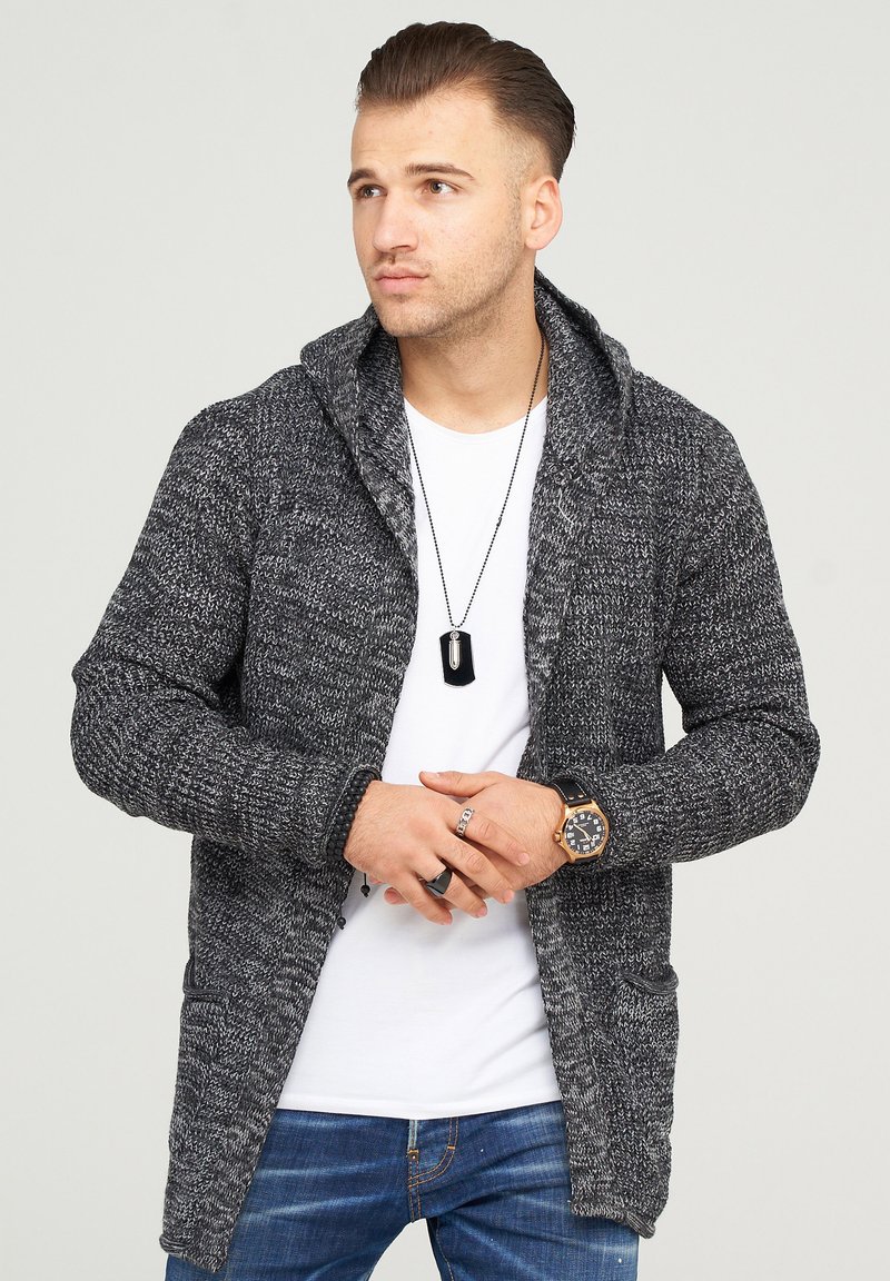 Gray knit cardigan with a hood, featuring textured yarn, two front pockets, and a relaxed fit, worn over a white shirt.