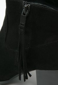 Czarne zamszowe botki za kostkę z bocznym zamkiem błyskawicznym i frędzlami, z teksturowaną powierzchnią i szarym słupkowym obcasem.