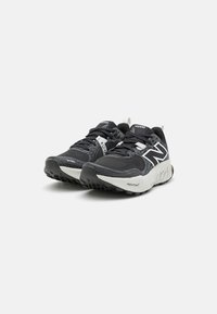 Scarpe da ginnastica nere con parte superiore in rete, dettagli bianchi, suola in gomma e design minimalista. Presentano una tecnologia di ammortizzazione etichettata "FRESH FOAM."
