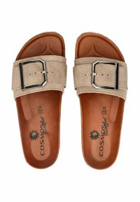 Des sandales à glisser en daim beige présentent une large bande avec une boucle en argent, une semelle intérieure texturée marron et un coussin de pied moulé.