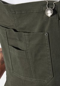 Olivgrüne Cargo-Hosen aus Baumwolle. Mit mehreren Taschen und einer Metallknopf-Verschluss mit Nähdetails. Weicher Textur, langlebiges Design.