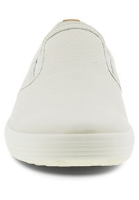 White slip-on shoe made of textured leather, featuring elastic side panels and a rubber sole. Minimalistic design with subtle detailing.
