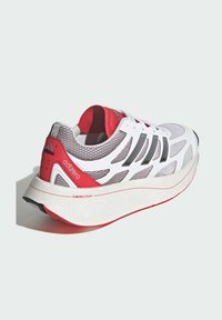 Adidas Adizero trkačka cipela s mrežastim gornjim dijelom u bijeloj i sivoj boji, crvenim naglascima i teksturiranom bijelom potplatu koji sadrži SwirlFoam tehnologiju.
