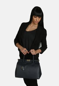 Borsa a mano in pelle blu navy con forma strutturata, doppi manici, dettagli in metallo dorato e finitura testurizzata. Presenta un piccolo dettaglio a forma di lucchetto.