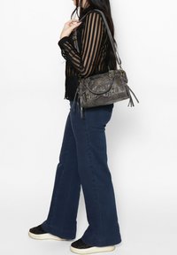 Sac à main en cuir gris avec des accents à franges, quincaillerie dorée et une forme structurée. Dispose d'une bandoulière et de plusieurs poches.