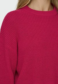 Maglione lavorato a maglia in fucsia vivace, con collo rotondo, vestibilità ampia e tessuto testurizzato, che presenta un motivo a trama aperta.