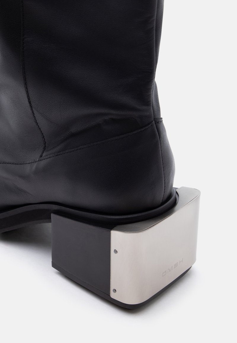 Stivale in pelle nera con tacco spesso e squadrato in metallo, finitura argento spazzolato e viti visibili.