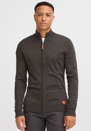 Cardigan de cierre en gris oscuro, hecho de lana texturizada. Presenta puños y bajo acanalados, con un acento de cuero cerca de la parte inferior.