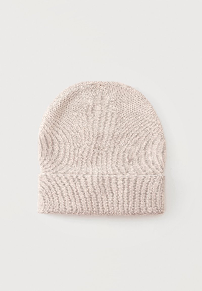 Bonnet tricoté beige clair avec bord replié, présenté à plat sur un fond clair uni.