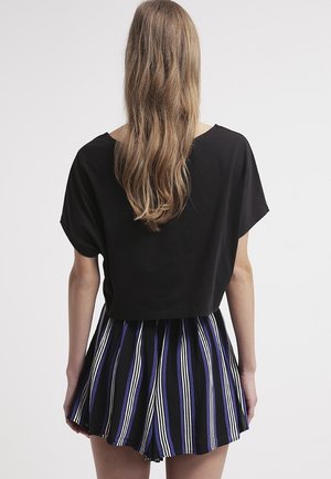 Sort cropped top parret med en stribet flared nederdel i nuancer af blå, sort og hvid, med lodrette linjer og et tekstureret stof.