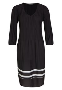 Schwarzes Kleid mit V-Ausschnitt, drei Viertelärmeln und vertikalen Falten. Der Saum hat horizontale weiße und schwarze Streifen. Glatte Stoffstruktur.