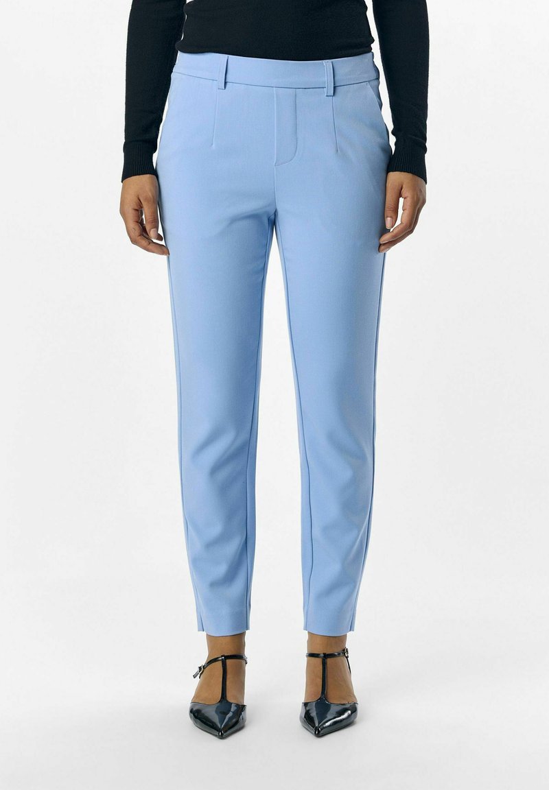 Světle modré kalhoty na míru z hladké tkaniny, s předními sklady a slim fit střihem. Spárováno s černými lodičkami na kotníkovém pásku.